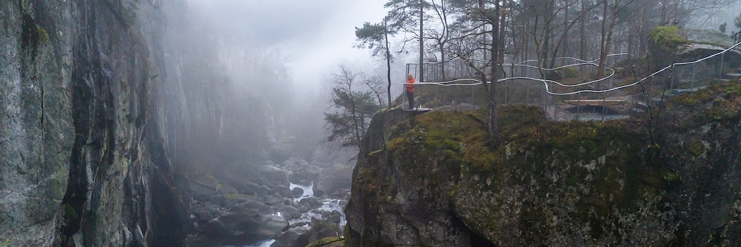 Ei kvinne står og ser utover elv og juv fra et utsiktspunkt.