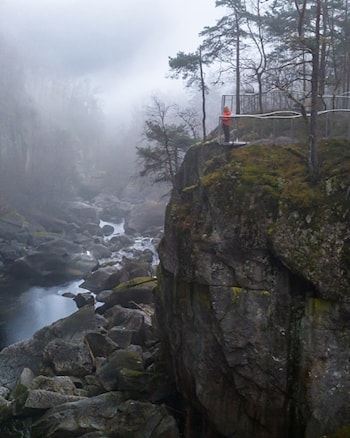 Ei kvinne står og ser utover elv og juv fra et utsiktspunkt.