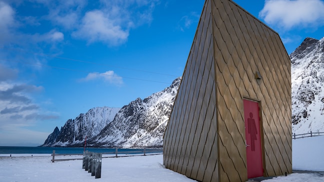 Trekantet toalettbygg i gyldne farger.