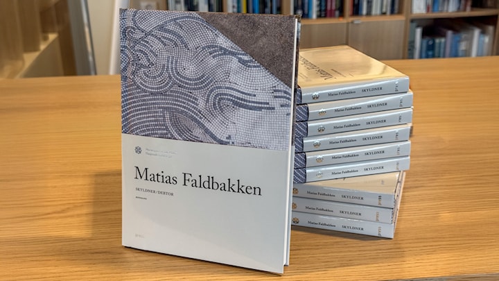 Ny kunstbok presentert foran flere kunstbøker som ligger stablet oppe på hverandre.