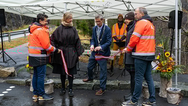  Six people stand together, mayor cuts the ribbon.