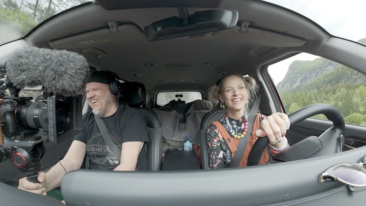 Mann og dame sitter i en bil og kjører. 