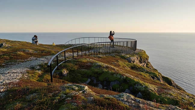 Illustrasjon av en person som tar bilde ved et utsiktspunkt ved storhavet.