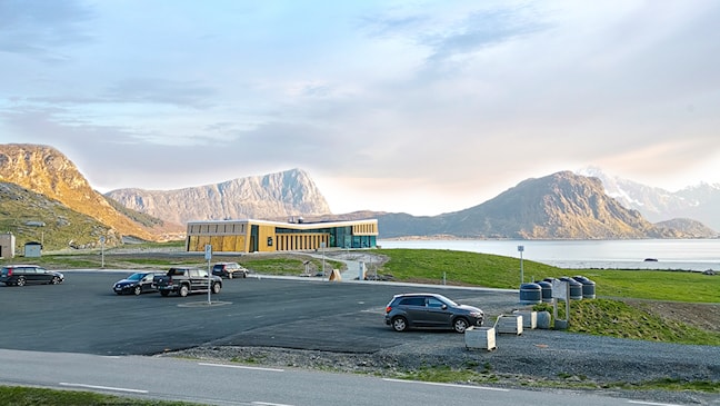 Større bygning i tre med glassfasader beliggende tett ved den flotte Hauklandstranda.