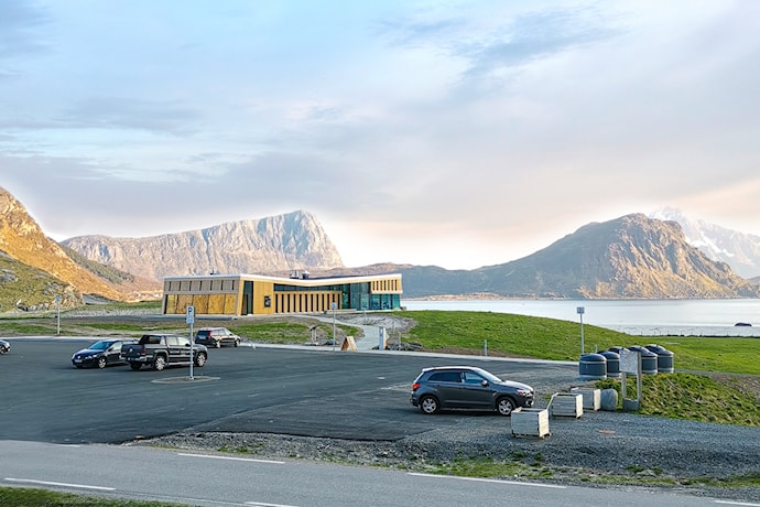 Større bygning i tre med glassfasader beliggende tett ved den flotte Hauklandstranda.