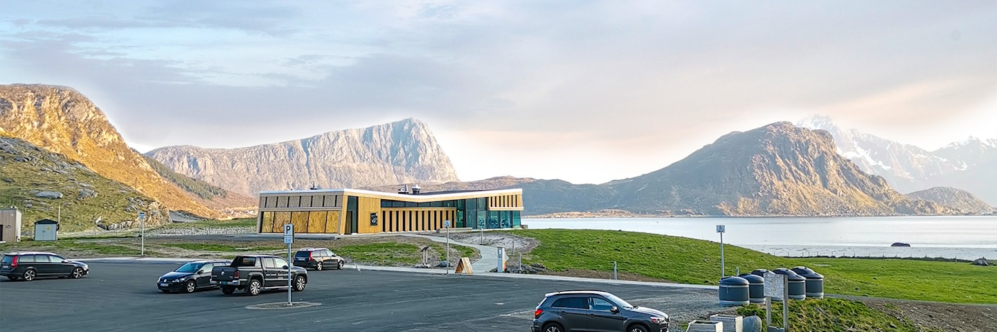 Større bygning i tre med glassfasader beliggende tett ved den flotte Hauklandstranda.