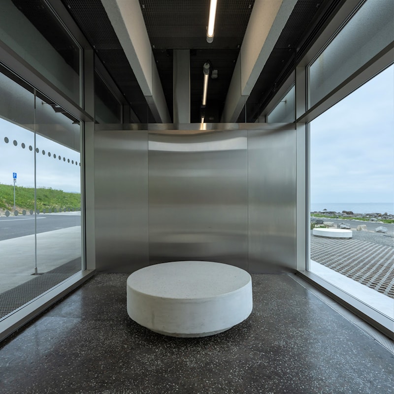 Stranda med havet og fjell i bakgrunnen.