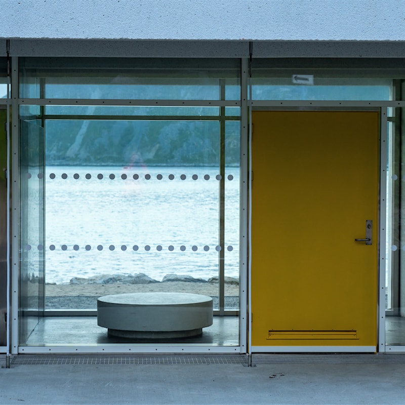 Inngangsparti med dør og vinduer med utsikt til havet.