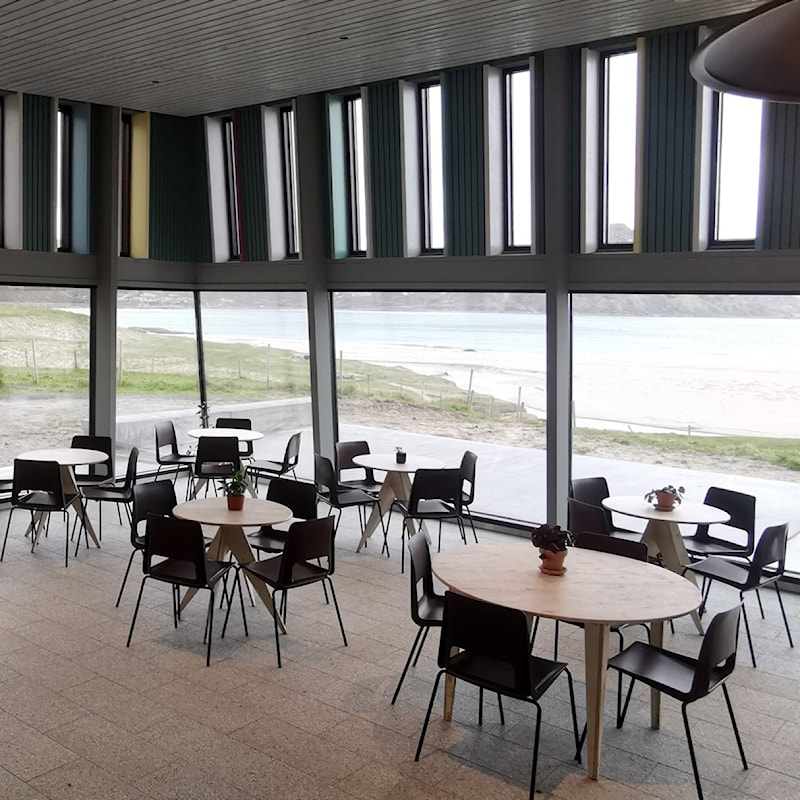 Kafe med utsikt til fjell og hvit sandstrand.