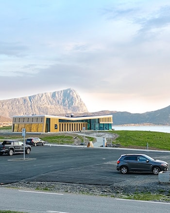 Større bygning i tre med glassfasader beliggende tett ved den flotte Hauklandstranda.