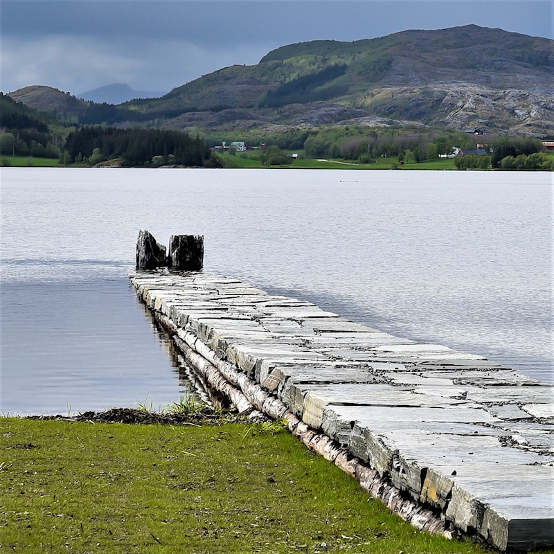 Steinpiren som strekker seg ut i vannet.