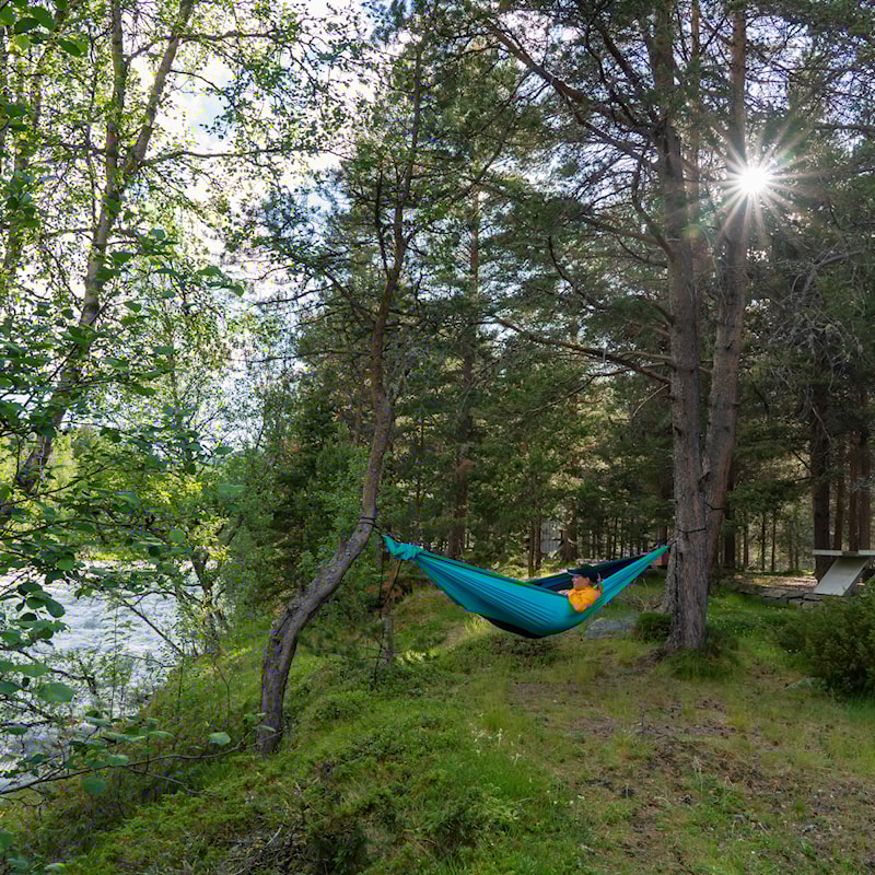 Ung kvinne i hengekøye ved elva.