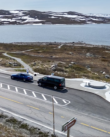 Luftfoto av parkeringsplass med fire biler i fjellandskap.