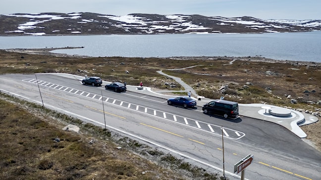 Luftfoto av parkeringsplass med fire biler i fjellandskap.