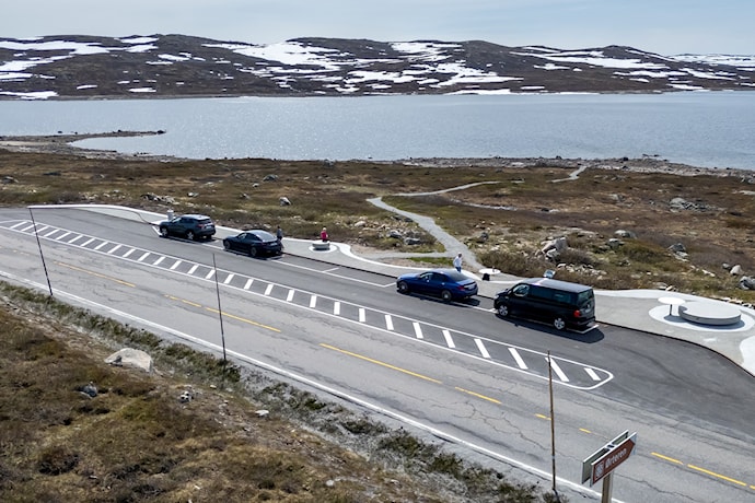 Luftfoto av parkeringsplass med fire biler i fjellandskap.