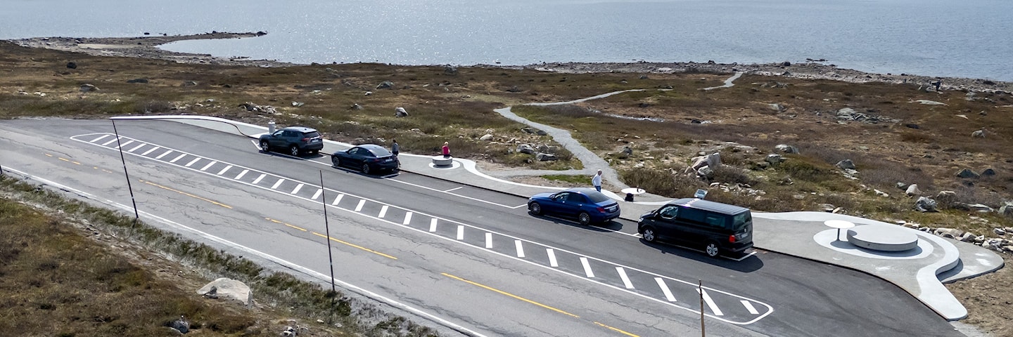 Luftfoto av parkeringsplass med fire biler i fjellandskap.