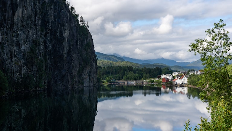 Bratte fjellsider og bebyggelse i lun vik i vestre enden av Suldalsvatnet.