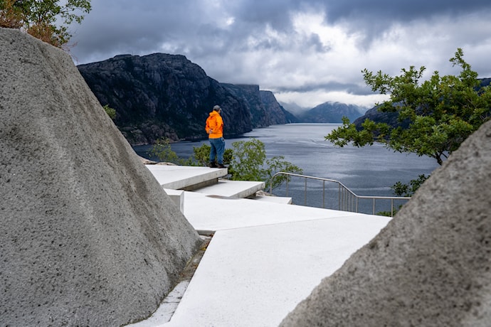 Betongsti går i en kløft av skråninger belagt med betong. Terrenget åpner seg opp med utsikt utover fjorden.